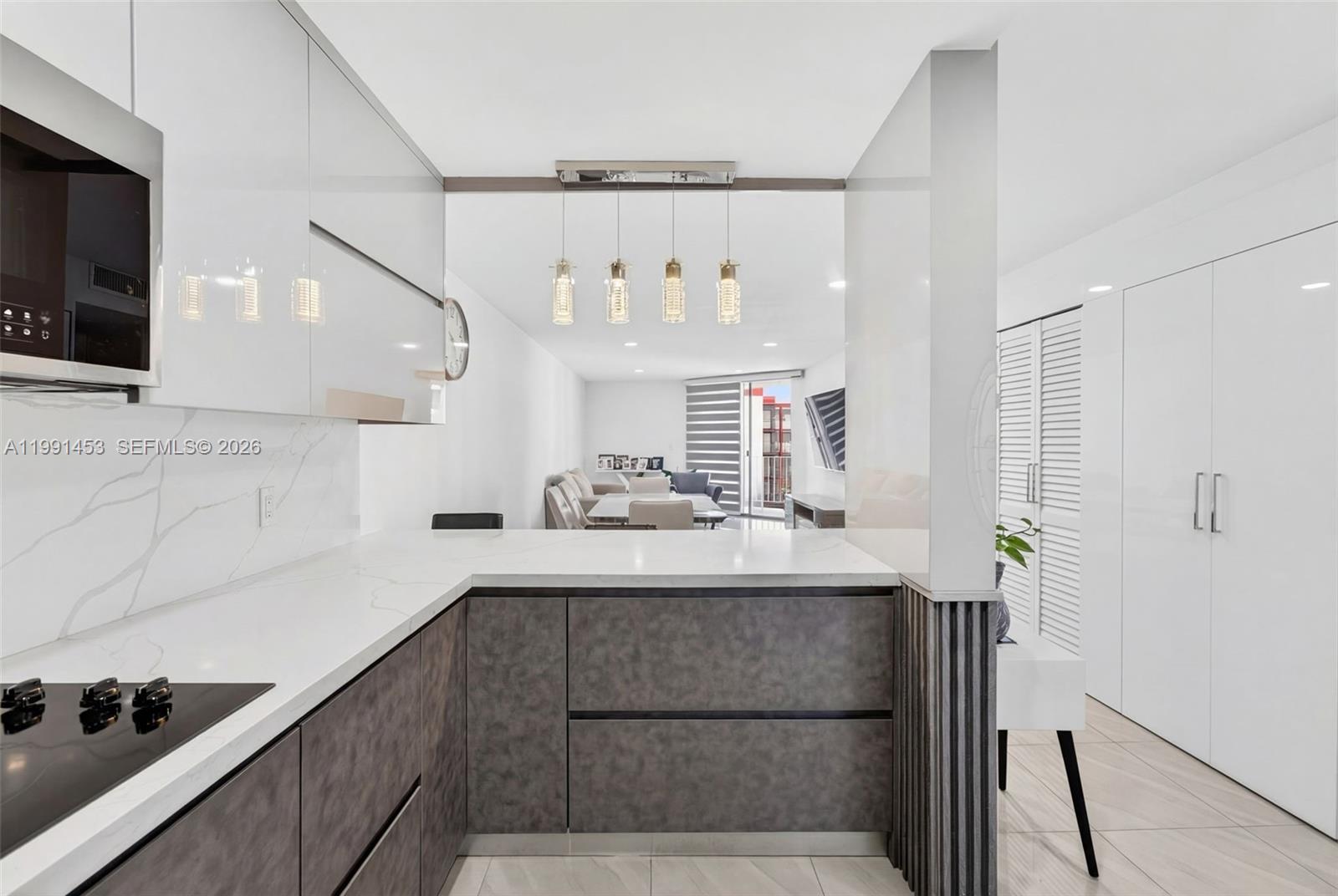 A modern kitchen features dark textured lower cabinets, white countertops, and a view into the living area — 1750 W 46th St # 412, Hialeah FL 33012, HIALEAH, FL