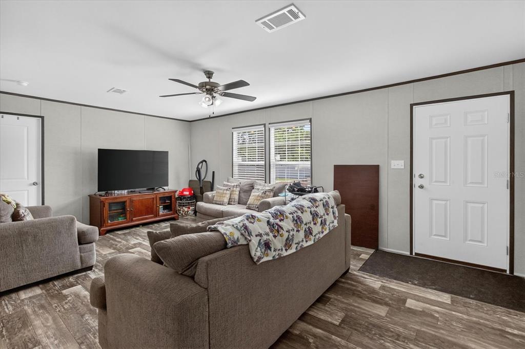 A living room with gray walls, wood-look flooring, a ceiling fan, and multiple sofas — 5139 ORLANDO AVENUE, BROOKSVILLE, FL