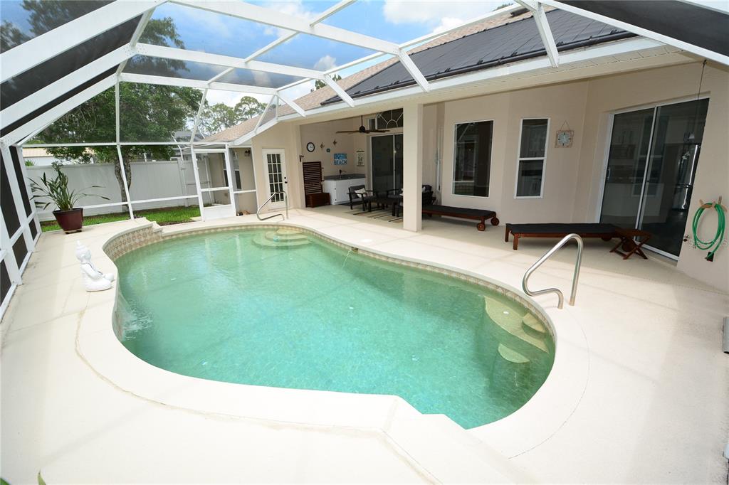 A screened-in patio features a swimming pool with steps and a beige concrete deck — 18 WELLWATER DRIVE, PALM COAST, FL