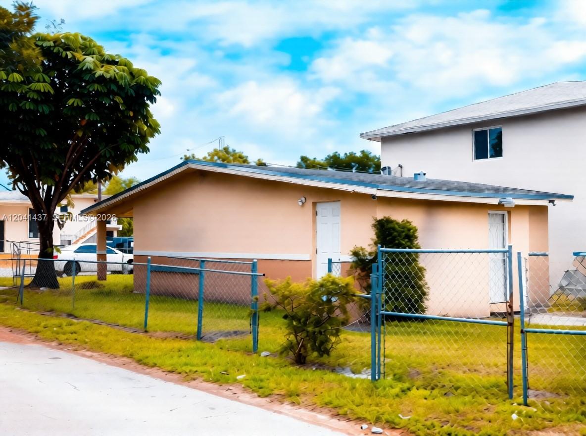 A single-story peach-colored house with a chain-link fence and a large tree in front — 1896 NW 64th St # 1, Miami FL 33147, MIAMI, FL