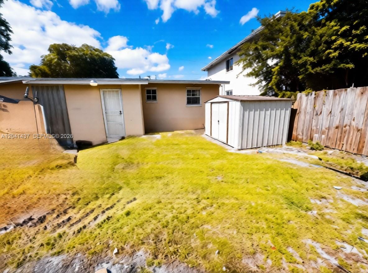 A backyard features a tan house exterior, a metal storage shed, and a wooden fence — 1896 NW 64th St # 1, Miami FL 33147, MIAMI, FL