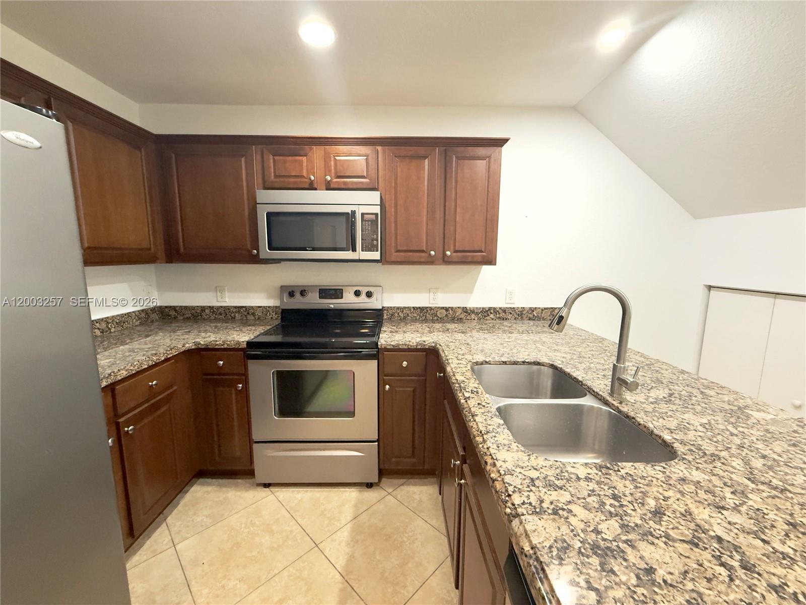 A kitchen with wood cabinets, granite countertops, and a breakfast bar with three stools — 1000 Palm Trl # 6, Delray Beach FL 33483, DELRAY BEACH, FL