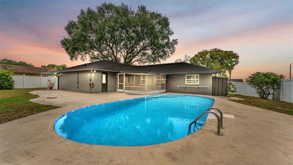 A backyard with a swimming pool, concrete patio, and a single-story house with a tree — 4301 ORANGEWOOD LOOP E, LAKELAND, FL