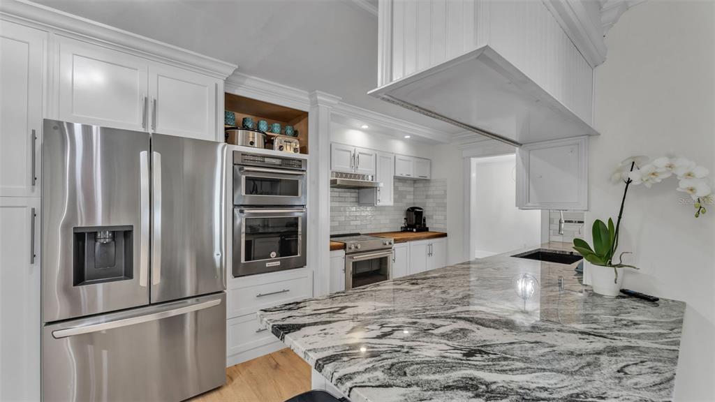 A modern kitchen features white cabinetry, stainless steel appliances, and a large granite island — 4301 ORANGEWOOD LOOP E, LAKELAND, FL