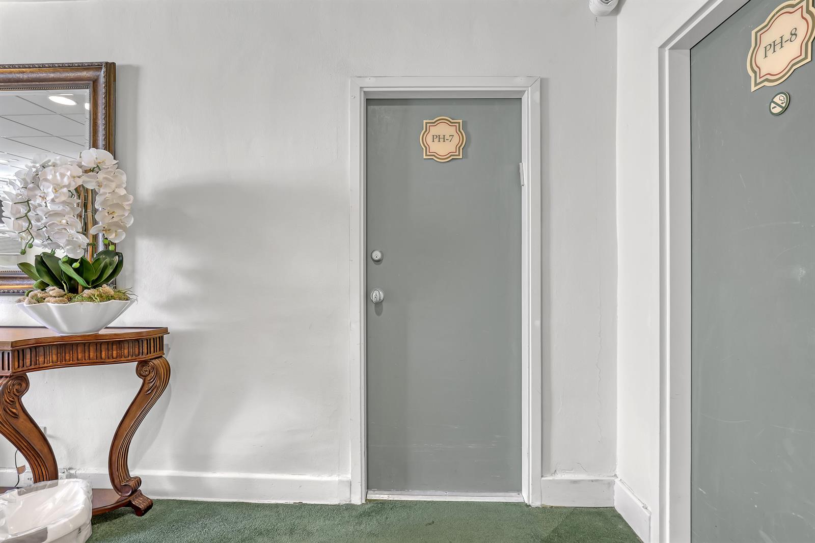 A hallway features two grey doors labeled PH-7 and PH-8 next to a wooden console table — 235 Sunrise Avenue, Palm Beach FL 33480, PALM BEACH, FL