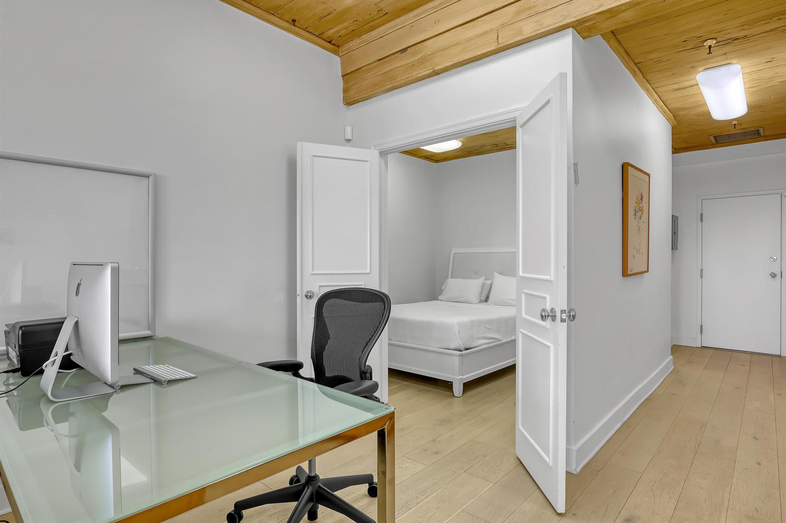 A home office with a glass desk leads into a bedroom through double doors — 235 Sunrise Avenue, Palm Beach FL 33480, PALM BEACH, FL