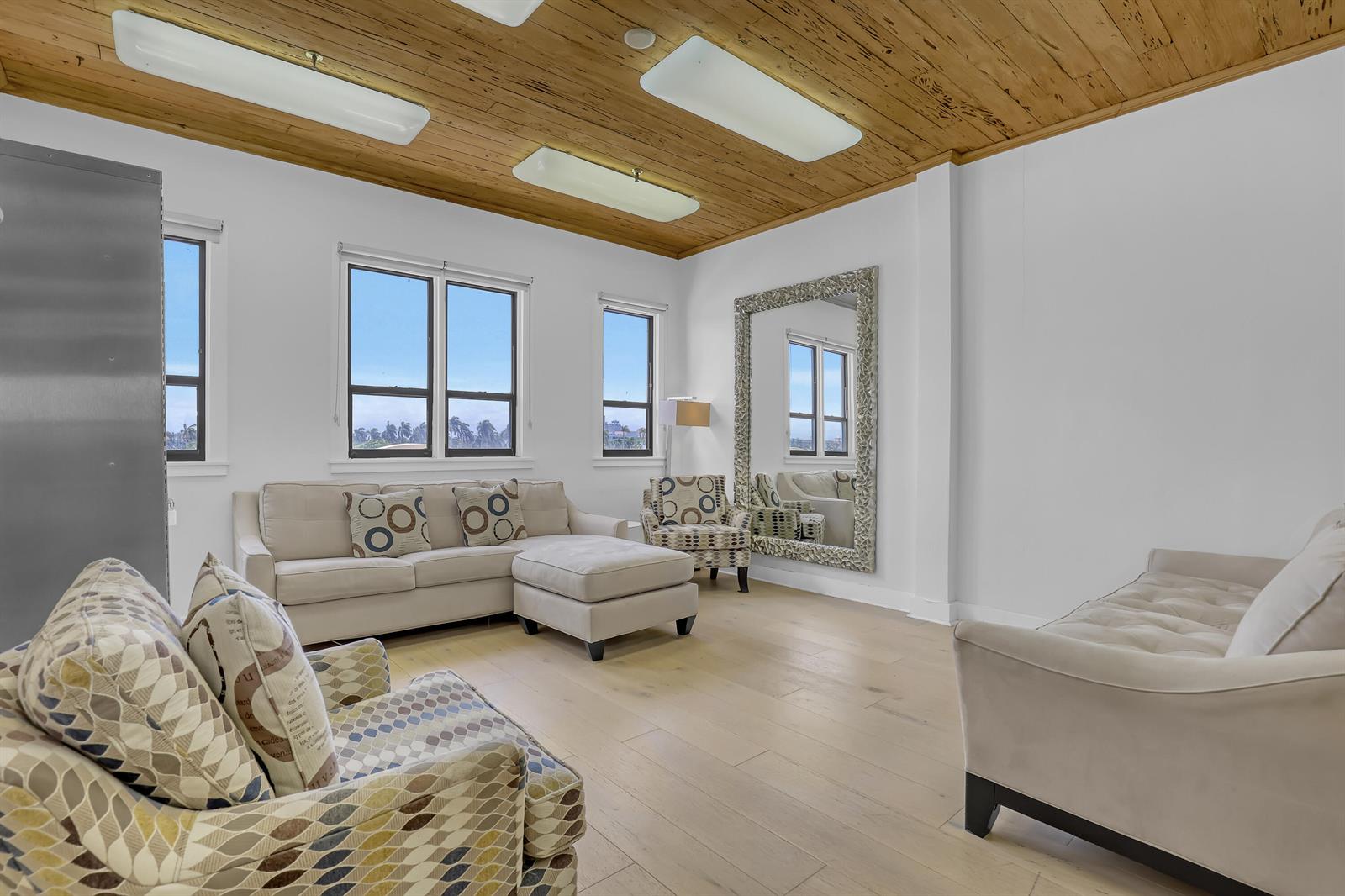 A living room features a wood-paneled ceiling, light hardwood floors, and multiple seating areas — 235 Sunrise Avenue, Palm Beach FL 33480, PALM BEACH, FL