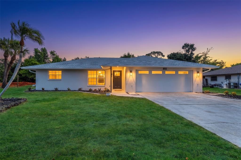 A single-story house with a white exterior, a two-car garage, and a green lawn — 855 MORNINGSIDE ROAD, VENICE, FL