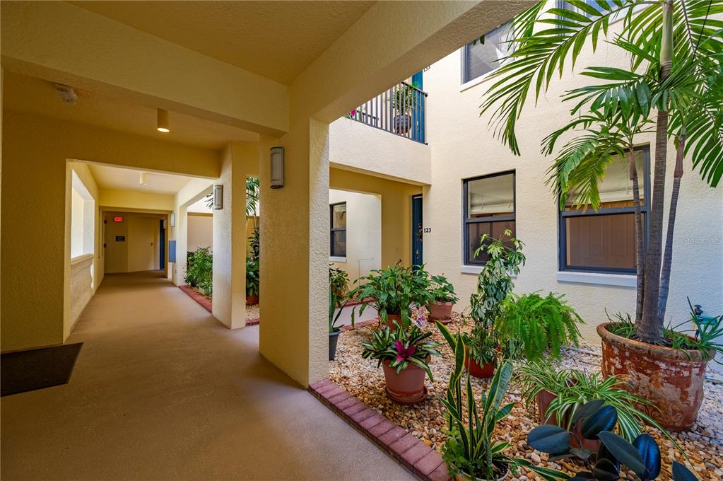 An outdoor courtyard with potted plants and a covered walkway leads to building entrances — 1340 ROCK DOVE COURT UNIT 123, PUNTA GORDA, FL