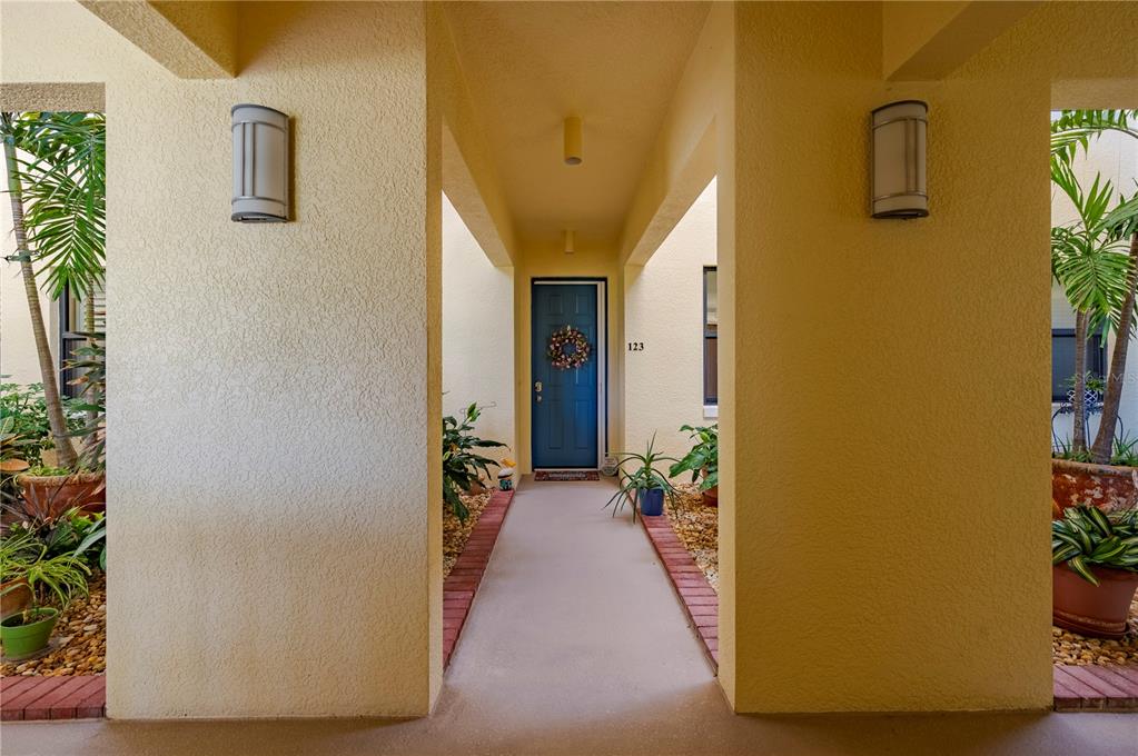 A blue front door with a wreath is at the end of a covered walkway — 1340 ROCK DOVE COURT UNIT 123, PUNTA GORDA, FL