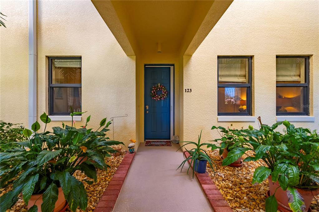 A blue front door with a wreath is centered between two windows under a portico — 1340 ROCK DOVE COURT UNIT 123, PUNTA GORDA, FL