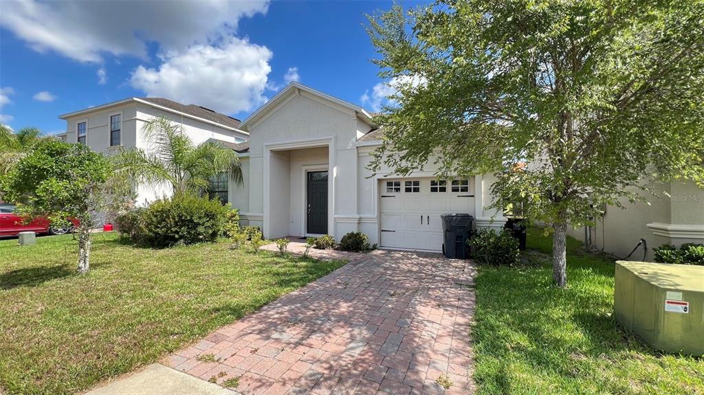 A one-story house with a white stucco exterior, a brick driveway, and a single-car garage — 2353 VICTORIA DRIVE, DAVENPORT, FL