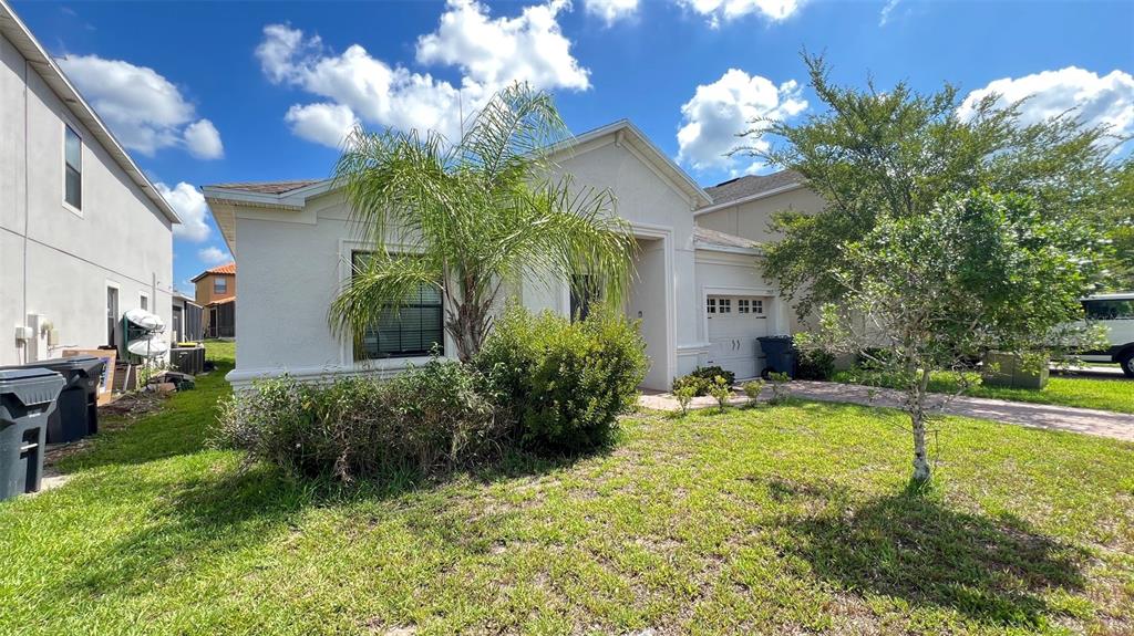 A single-story house with a palm tree, a small front yard, and a garage — 2353 VICTORIA DRIVE, DAVENPORT, FL