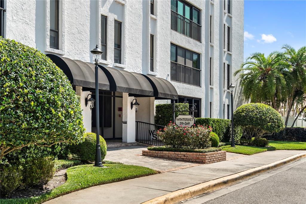 The exterior of a white multi-story apartment building features a black awning and landscaping — 269 E CANTON AVENUE UNIT 269, WINTER PARK, FL