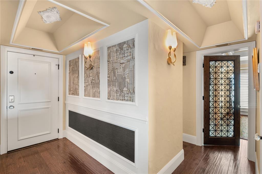 A foyer with hardwood floors, white wainscoting, city-themed wallpaper panels, and two doorways — 269 E CANTON AVENUE UNIT 269, WINTER PARK, FL