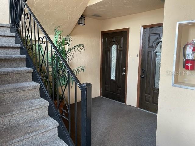 A staircase with a black metal railing leads to two dark brown entry doors — 4711 SANTA BARBARA BOULEVARD UNIT 1, CAPE CORAL, FL