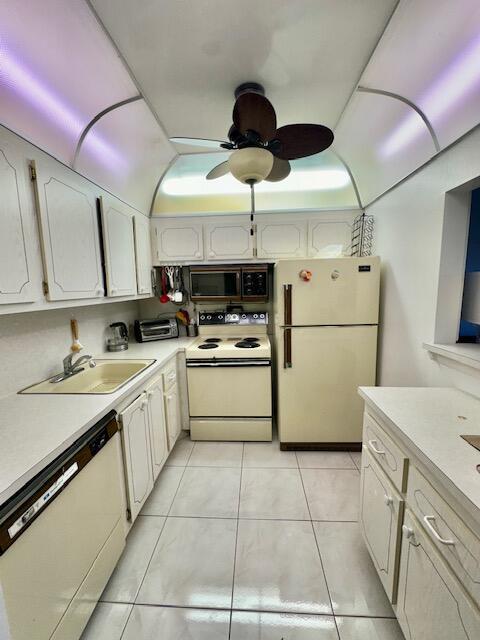 A galley kitchen features cream-colored cabinets, a ceiling fan, and white tile flooring — 30 Suffolk A, Boca Raton FL 33434, BOCA RATON, FL