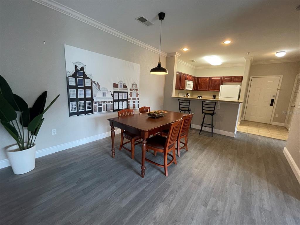 A dining area with a wooden table, chairs, and wall art opens to a kitchen — 1370 TUSCAN TERRACE UNIT 2307, DAVENPORT, FL