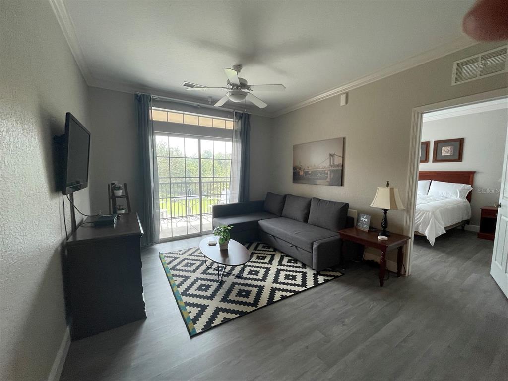 A living room with gray flooring, a sectional sofa, a patterned rug, and a balcony — 1370 TUSCAN TERRACE UNIT 2307, DAVENPORT, FL