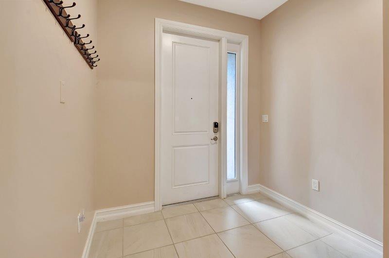 An entryway features beige walls, a white door with a sidelight, and light-colored tiled flooring — 10102 Akenside Drive, Boca Raton FL 33428, BOCA RATON, FL