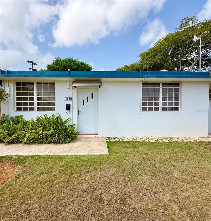 A white single-story house with a blue roof, a front door, and two grid-patterned windows — 139 L STREET RAMEY BASE, AGUADILLA, PR