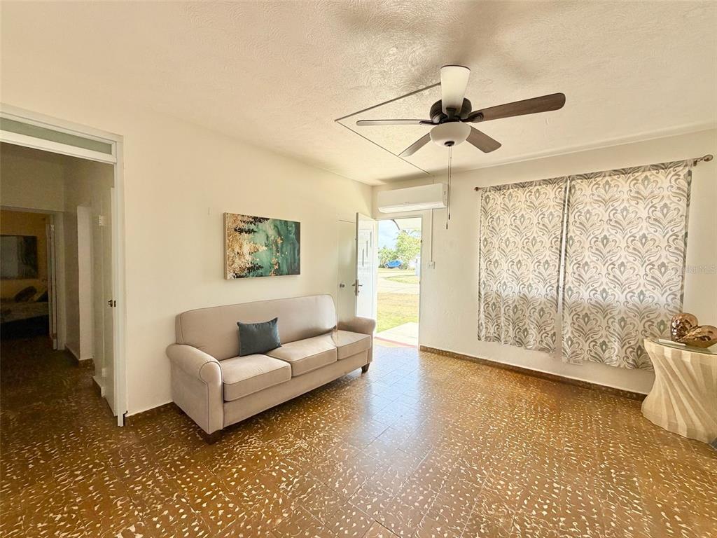 A living room features a beige sofa, patterned curtains, a ceiling fan, and tiled floors — 139 L STREET RAMEY BASE, AGUADILLA, PR