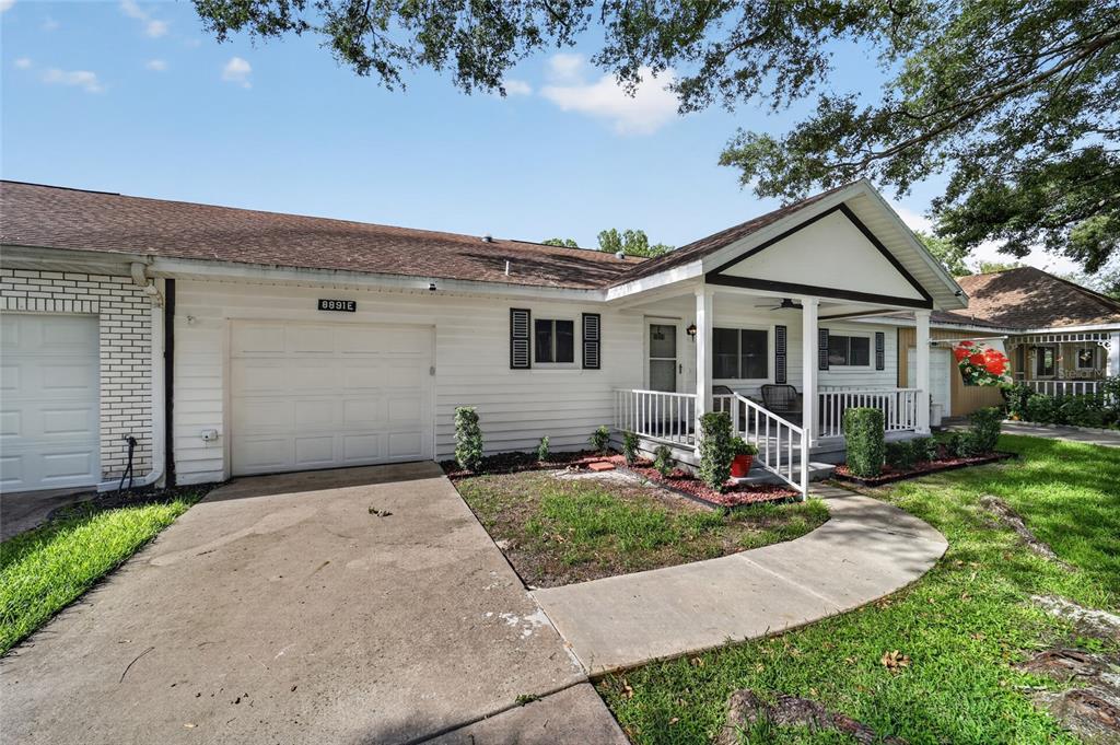 A white single-story house features a front porch, a concrete driveway, and a garage — 8891 SW 96TH LANE UNIT E, OCALA, FL
