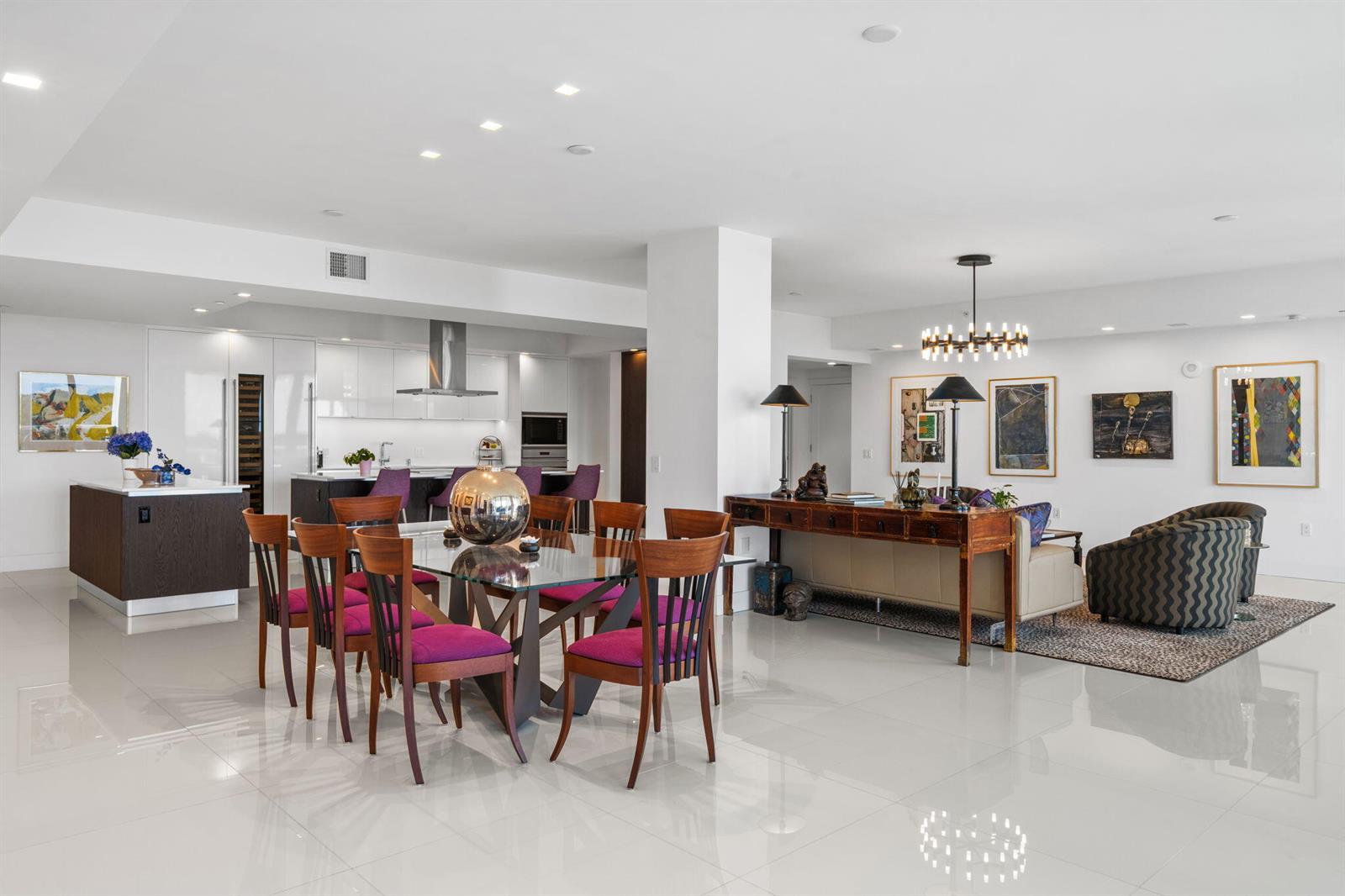 An open-concept living and dining area features white tile floors, purple chairs, and modern art — 20155 Boca West Drive # A404, Boca Raton FL 33434, BOCA RATON, FL