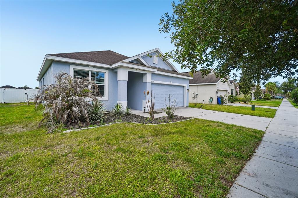 A light blue single-story house with a two-car garage and a front yard — 14310 ALISTAR MANOR DRIVE, WIMAUMA, FL