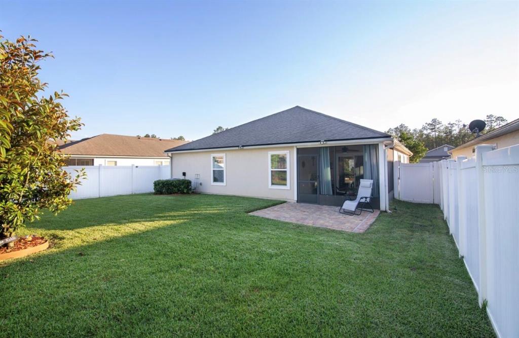 A covered front porch features light-colored siding, two wicker chairs, and a light blue door — 144 S HUMMINGBIRD PLACE, PALM COAST, FL