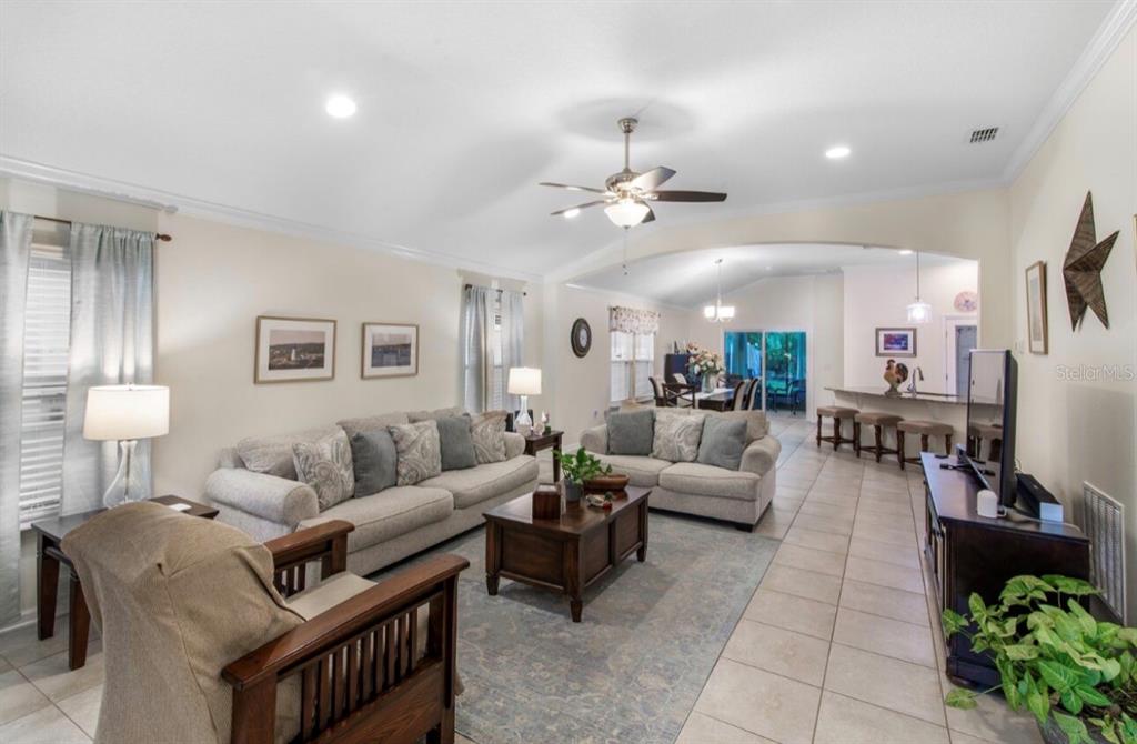 A living room with tile floors, two sofas, a coffee table, and an open kitchen — 144 S HUMMINGBIRD PLACE, PALM COAST, FL