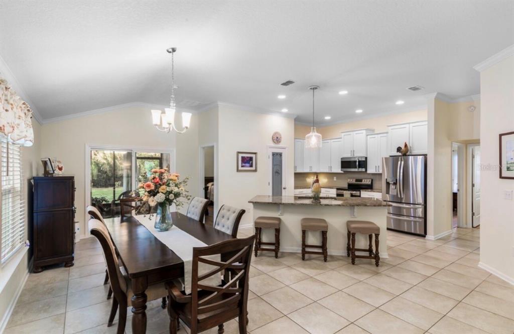A dining area with a wooden table flows into an open kitchen with granite countertops — 144 S HUMMINGBIRD PLACE, PALM COAST, FL