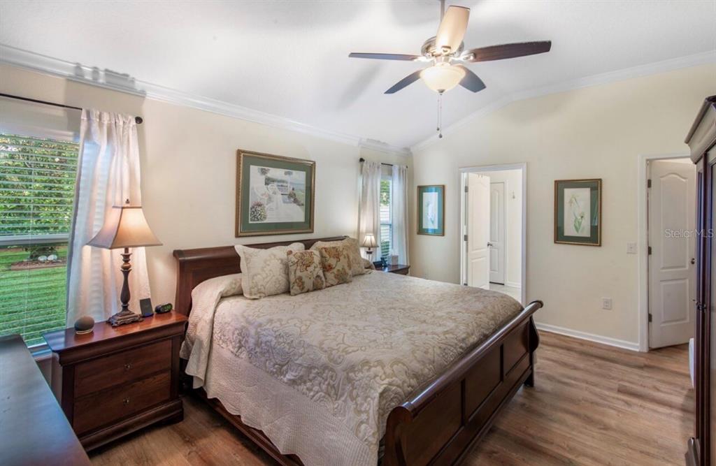 A bedroom with a wooden bed frame, ceiling fan, and light-colored walls and flooring — 144 S HUMMINGBIRD PLACE, PALM COAST, FL