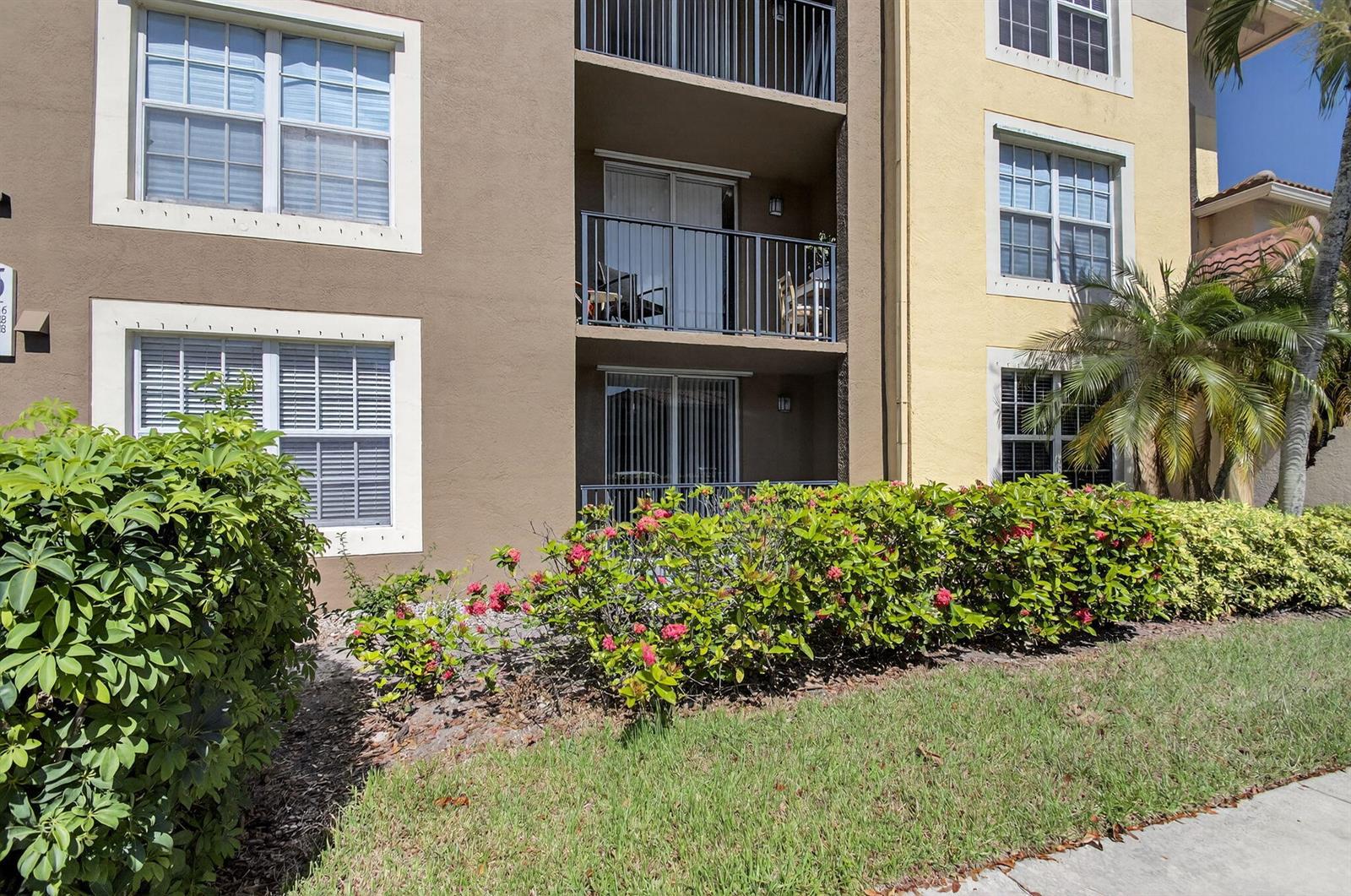An exterior view of a multi-story apartment building with balconies and landscaped bushes — 15035 Michelangelo Boulevard # 105, Delray Beach FL 33446, DELRAY BEACH, FL