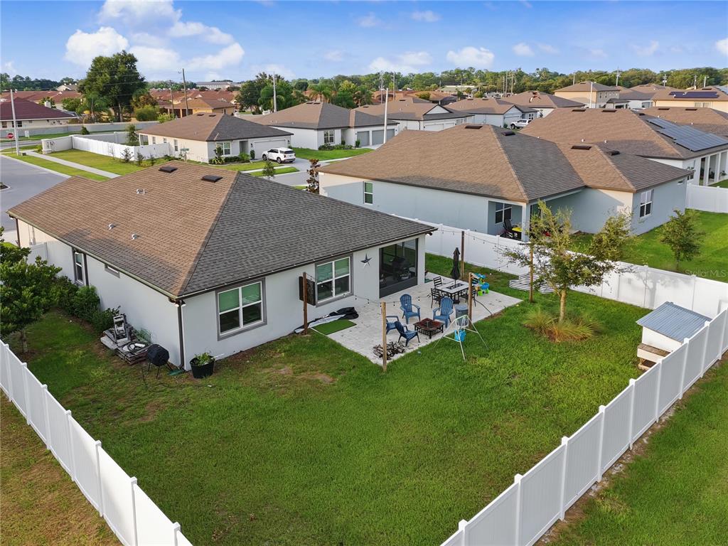An aerial view of a suburban house backyard featuring a patio, lawn, and white fence — 1067 MICHELANGELO LANE, WINTER HAVEN, FL