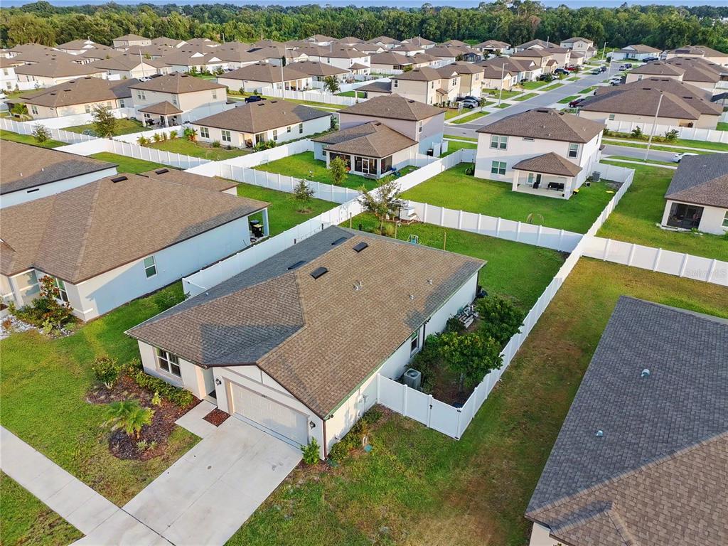 An aerial view shows a suburban neighborhood with single-family homes and white vinyl fences — 1067 MICHELANGELO LANE, WINTER HAVEN, FL