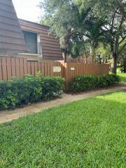 A brown wooden fence encloses a patio area in front of a multi-story residential building — 3017 30th Court, Jupiter FL 33477, JUPITER, FL