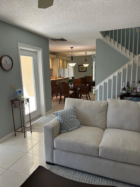 A living room with a light-colored sofa, tiled floors, and a view into a dining area — 3017 30th Court, Jupiter FL 33477, JUPITER, FL