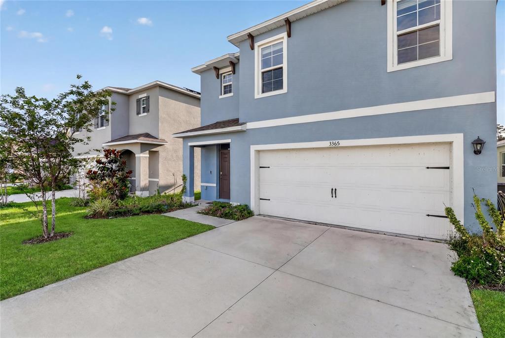 A two-story blue house with a white garage door and a concrete driveway — 3365 COSTELLO CIRCLE, WINTER HAVEN, FL