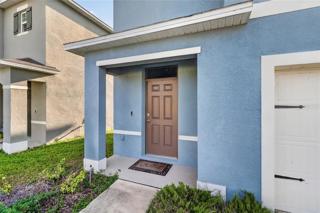 The exterior of a blue house features a brown front door and a covered porch — 3365 COSTELLO CIRCLE, WINTER HAVEN, FL