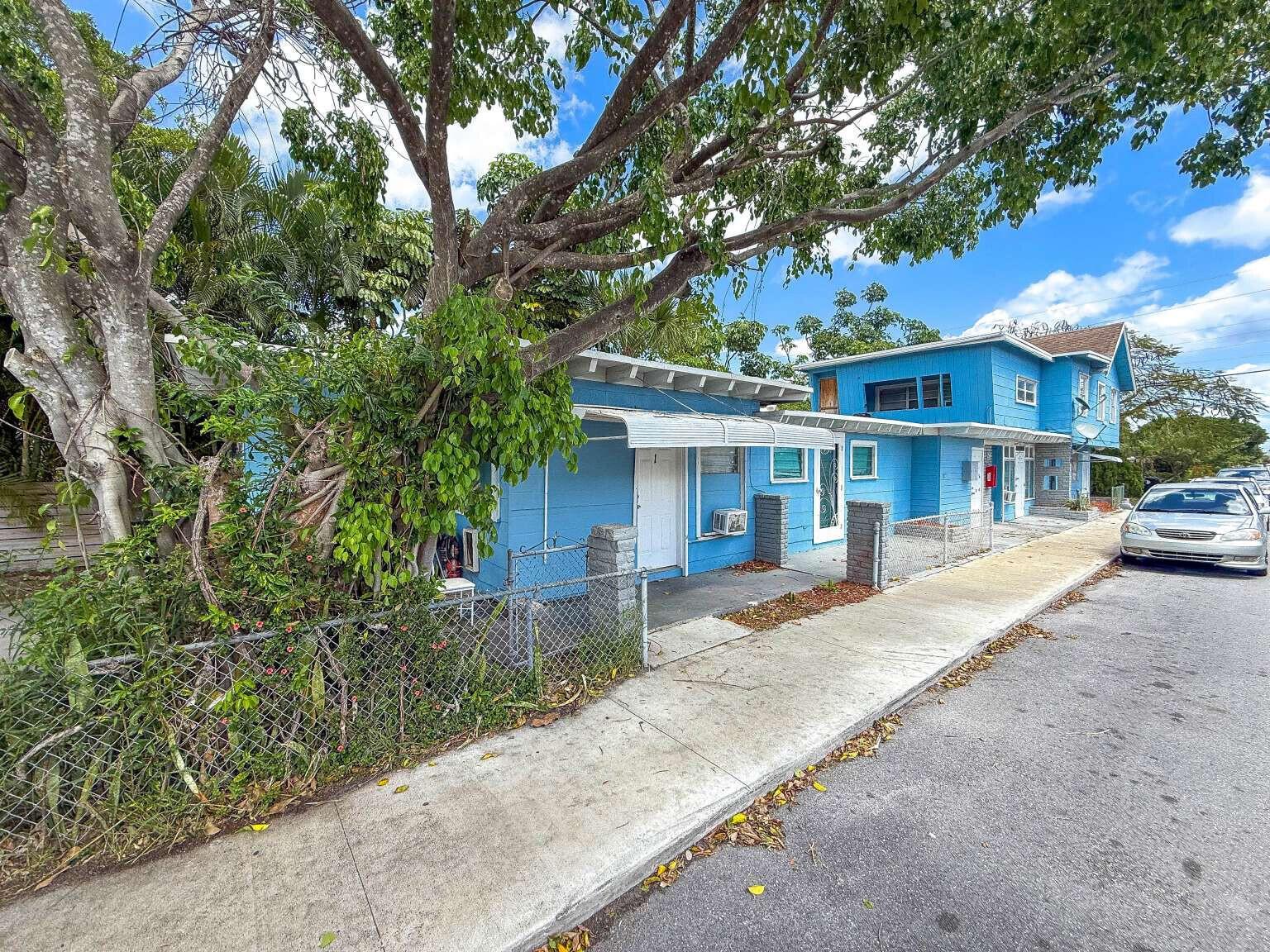 A blue, multi-unit residential building sits along a sidewalk next to a large tree — 714 N 4th Ave Avenue N, FL 33460, FL