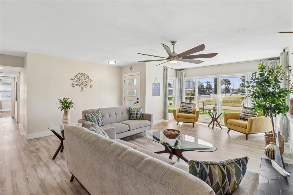 A living room features light wood flooring, two grey sofas, and two yellow armchairs — 133 PARK AVENUE, DAYTONA BEACH, FL