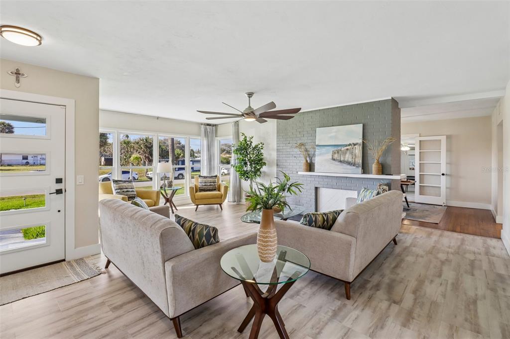 A living room features light wood flooring, a gray brick fireplace, and large windows — 133 PARK AVENUE, DAYTONA BEACH, FL
