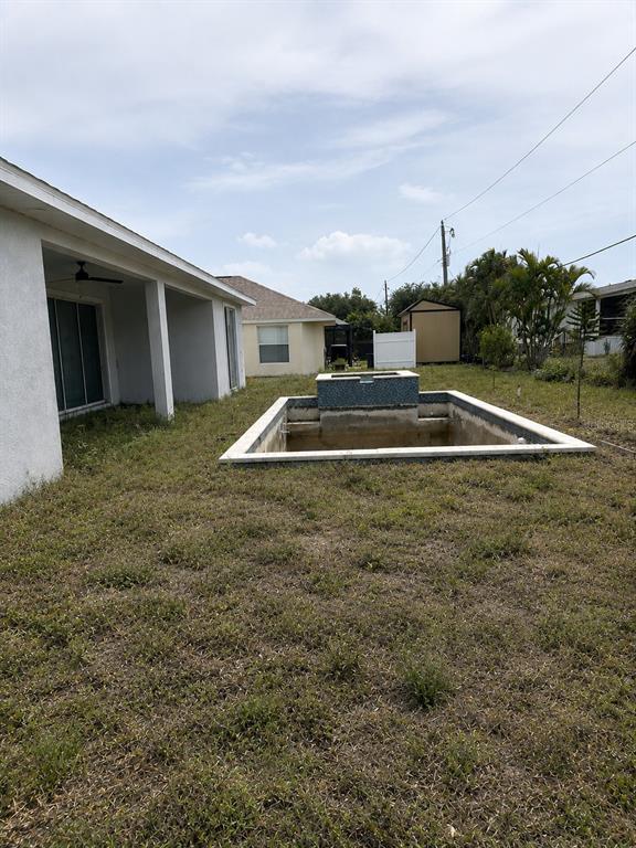 An empty, unfinished rectangular pool with a raised tiled spa sits in a grassy backyard — 9057 BANTRY BAY BOULEVARD, ENGLEWOOD, FL
