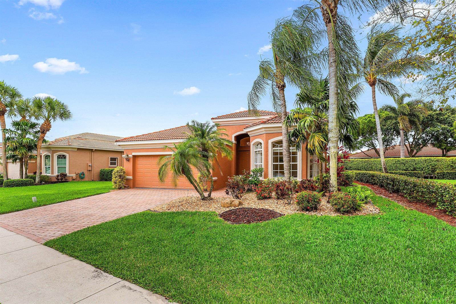 A single-story orange stucco house with a tile roof, paved driveway, and palm trees — 8240 Parini Way, Lake Worth FL 33467, LAKE WORTH, FL