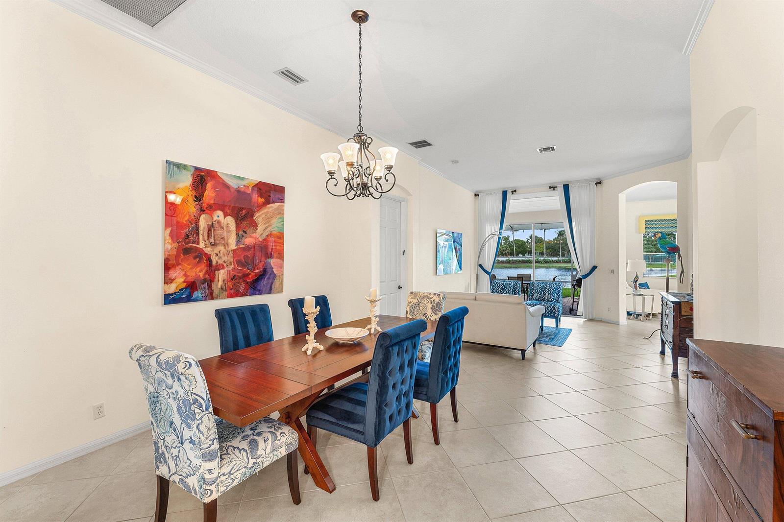 A dining area with a wooden table and blue chairs opens into a living room — 8240 Parini Way, Lake Worth FL 33467, LAKE WORTH, FL