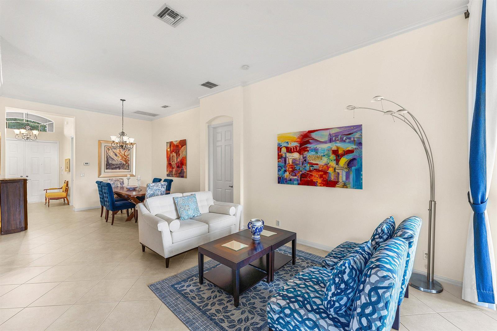 A living and dining area with tile floors, blue patterned furniture, and colorful wall art — 8240 Parini Way, Lake Worth FL 33467, LAKE WORTH, FL