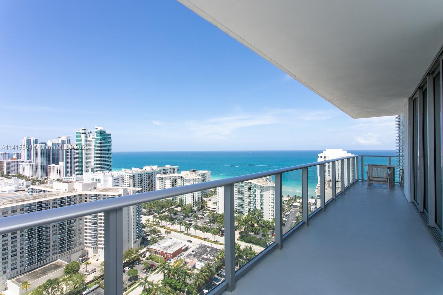 A high-rise balcony overlooks a city skyline and the ocean under a clear blue sky — 4010 S Ocean Dr # 1201, Hollywood FL 33019, HOLLYWOOD, FL