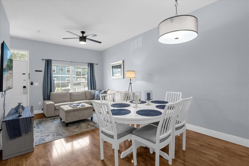 A dining area and living room with a sectional sofa, white table, and hardwood floors — 2213 SAN VITTORINO CIRCLE UNIT 106, KISSIMMEE, FL