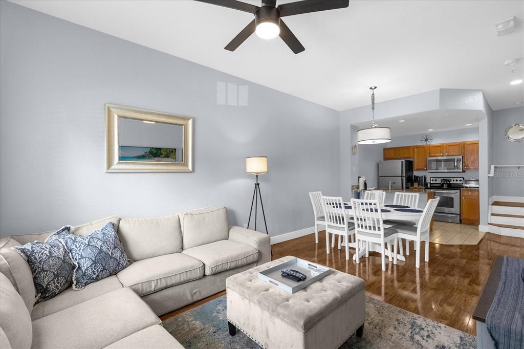 A living room with a sectional sofa and ottoman opens into a dining area and kitchen — 2213 SAN VITTORINO CIRCLE UNIT 106, KISSIMMEE, FL